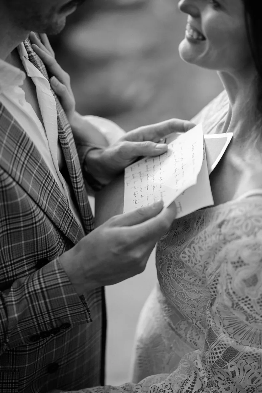 Reading handwritten vows from a letter, photographed in black and white