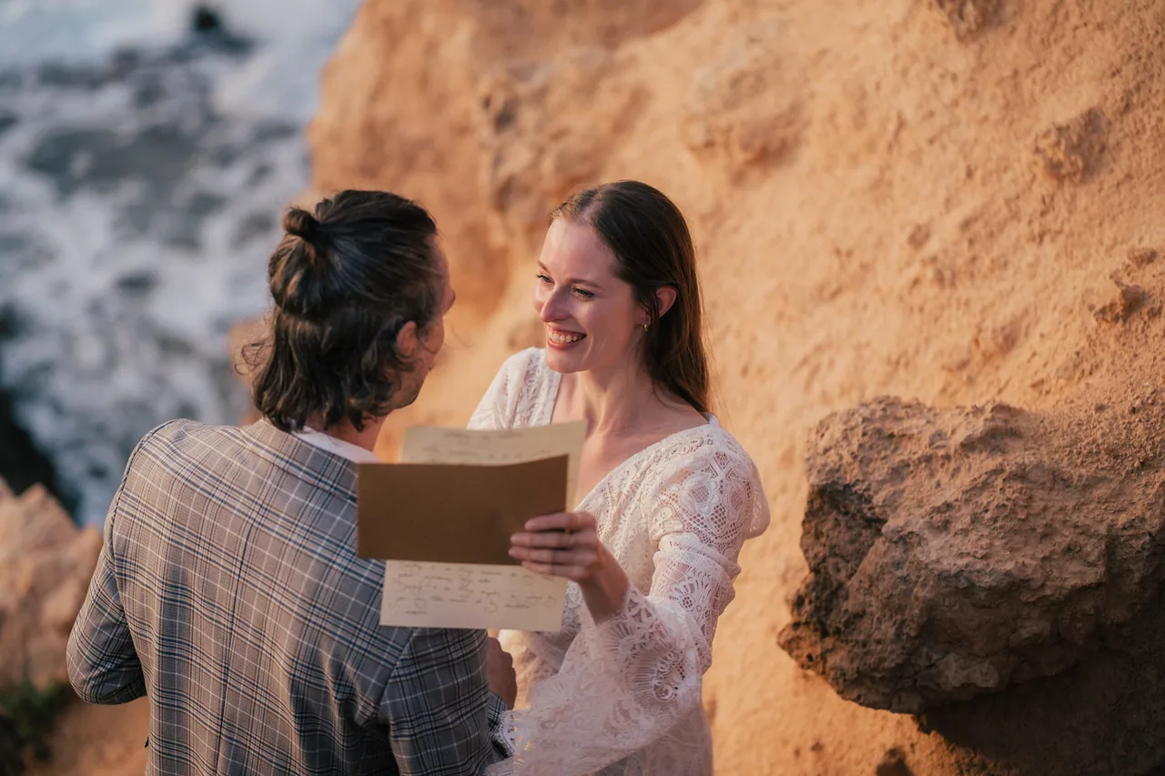 A couple reading vows on a golden cliff, one of the parts of an elopement money can't improve