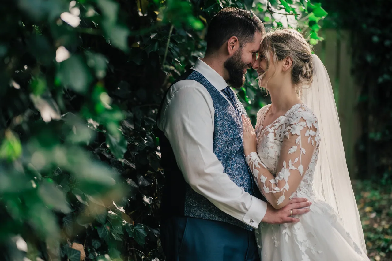 A wedding couple laughing together in green garden light on their small wedding day