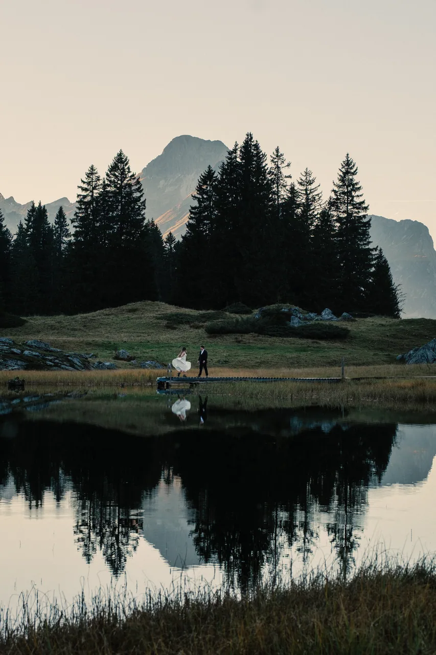 A still alpine lake mirroring forest and peak